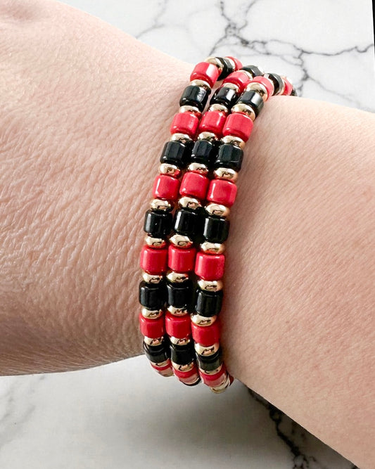 Red and black beaded bracelet trio with gold metal bead details shown layered as a stacked bracelet set.