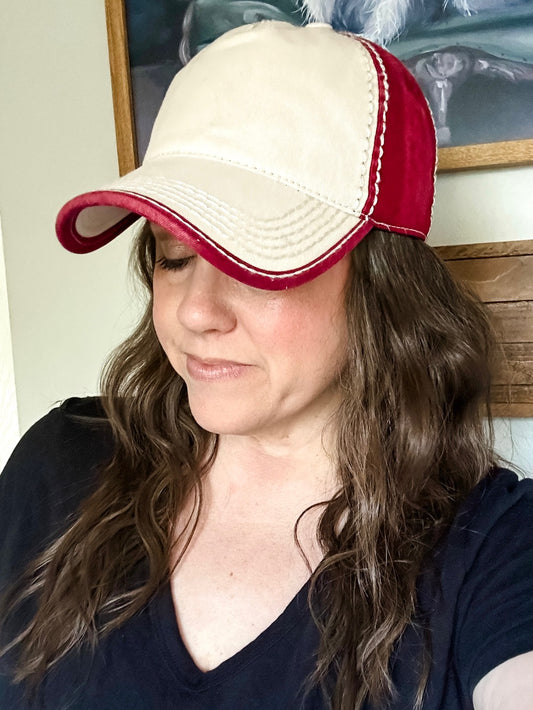 Woman wearing a cardinal red and ivory two tone washed baseball cap with curved brim and contrast stitching.
