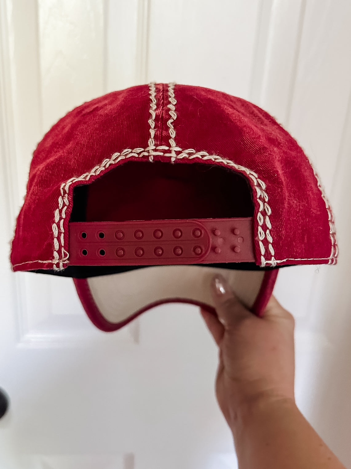 Close view of cardinal red washed baseball cap showing adjustable snapback closure and contrast stitching.