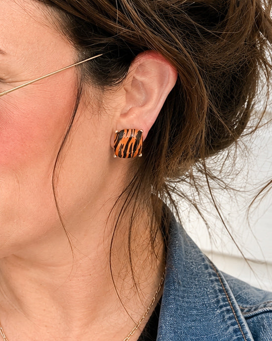 Woman wearing Tiger Trail tiger print stud earrings with gold-tone settings for a stylish football game day look.