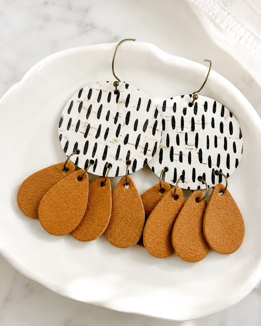 Neutral cork and genuine leather earrings displayed in a white ceramic jewelry dish.
