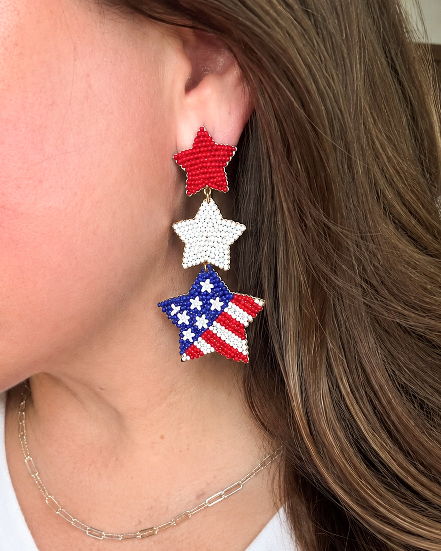 Woman wearing Under the Stars patriotic seed bead star earrings with red white and blue flag design