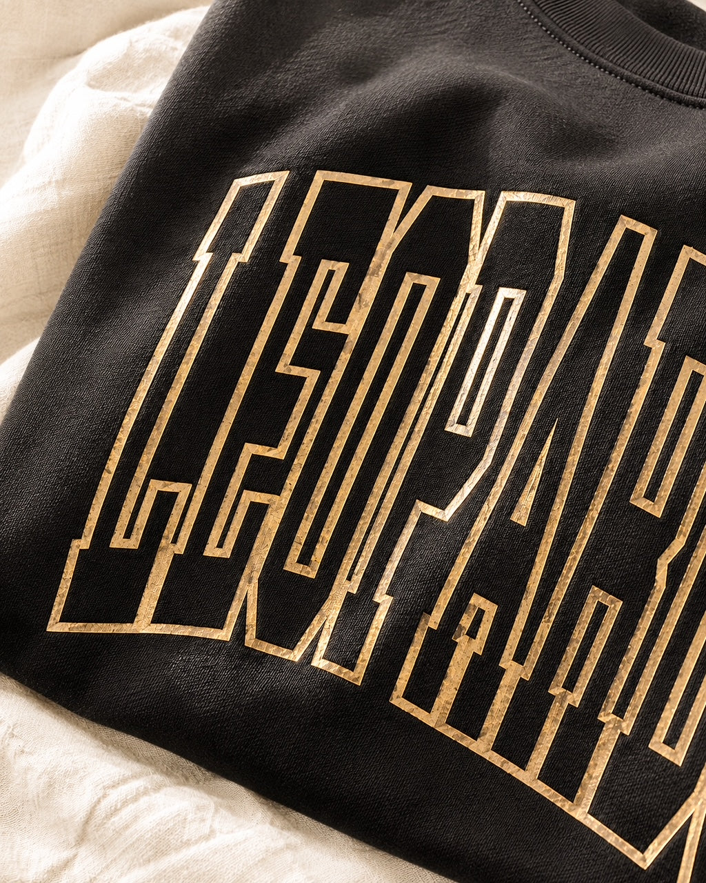 Close-up of the metallic-gold LEOPARDS collegiate lettering on the black Varsity Edit shirt