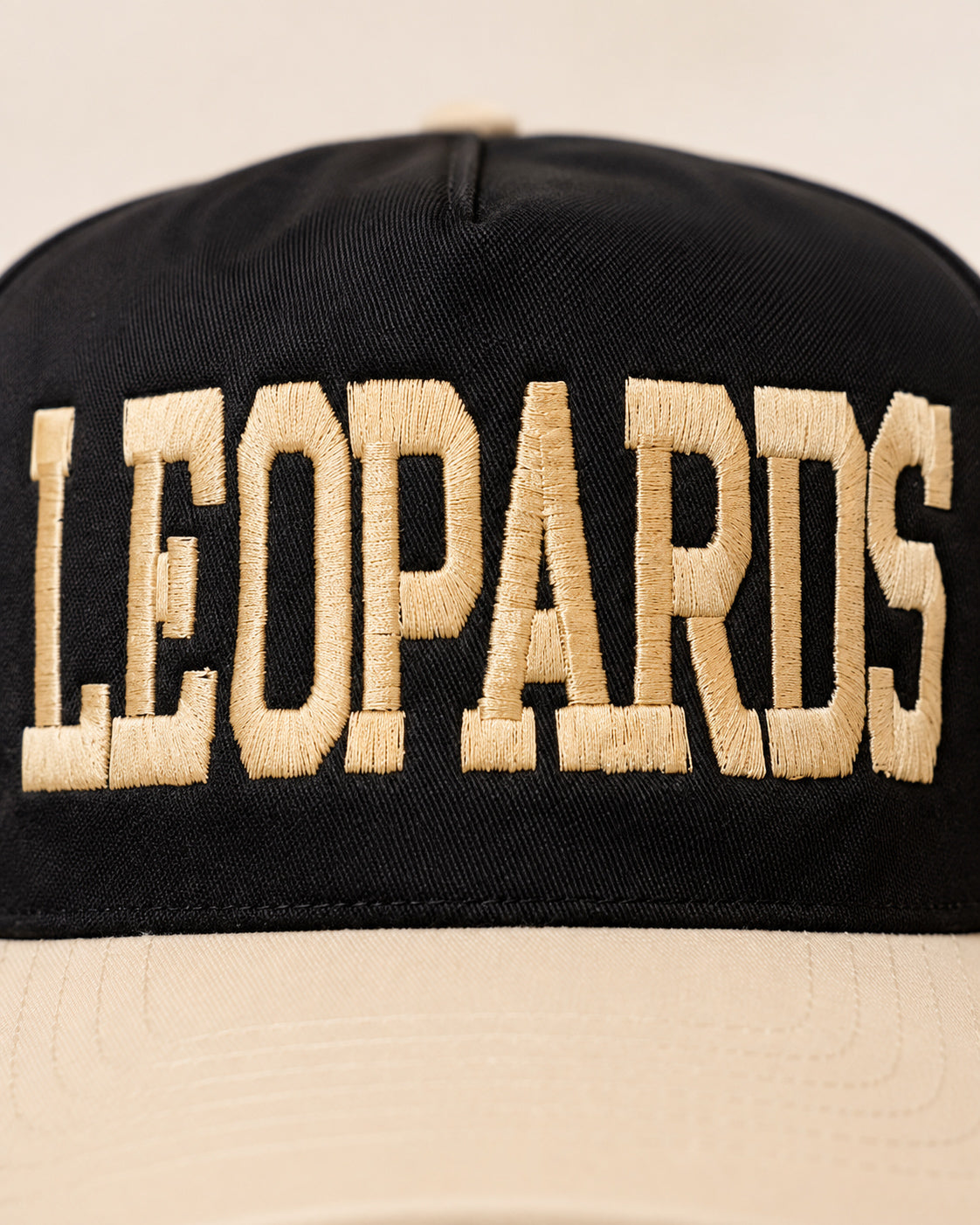 Close-up of the dimensional ivory varsity-style LEOPARDS lettering embroidered on the black hat