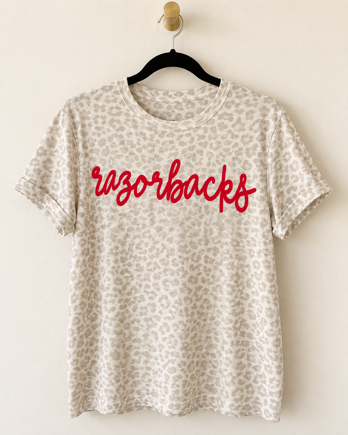 Light leopard print Wild Script Tee hanging on a wooden hanger with custom script lettering across the front.