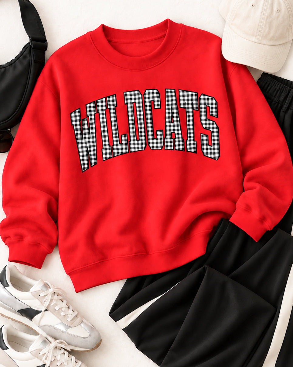 Red Wildcats gingham sweatshirt styled with black striped pants, retro sneakers, a cream cap, and a black bag.