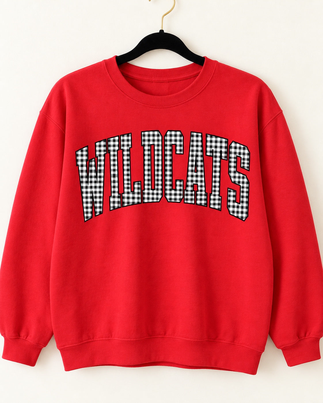 Red Wildcats crewneck sweatshirt with arched black-and-white gingham lettering on a black velvet hanger.