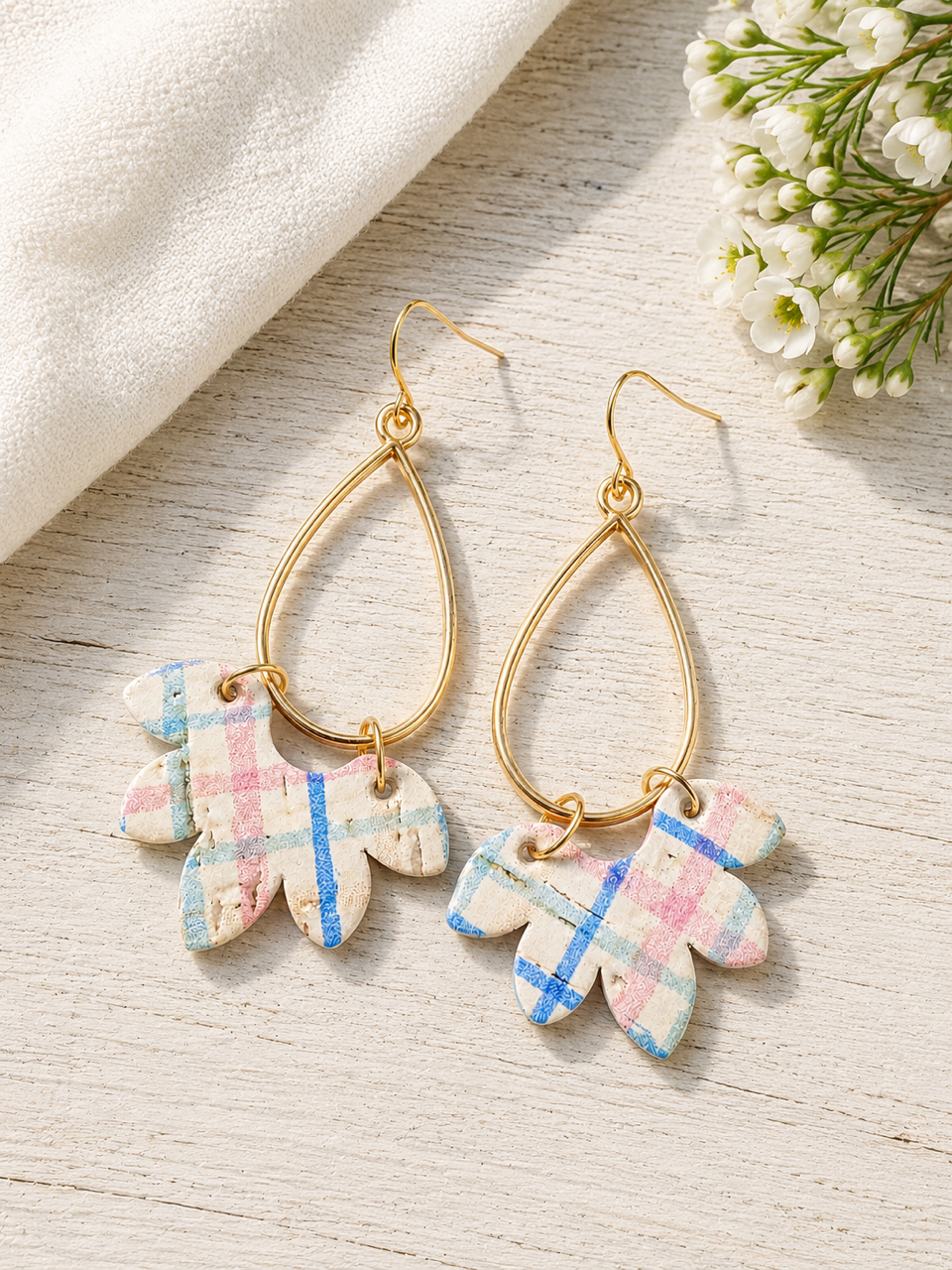 Handmade Wildflower Patch cork earrings with pastel plaid design styled on a light natural wood surface.