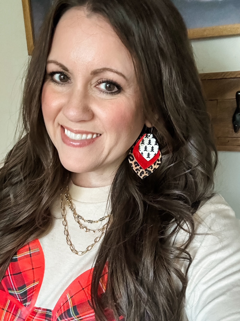 Model wearing the large Wildwood Noel Earrings featuring layered leopard print, red shimmer, and pine tree cork on hoops, paired with the Christmas Morning Long-Sleeve Tee.