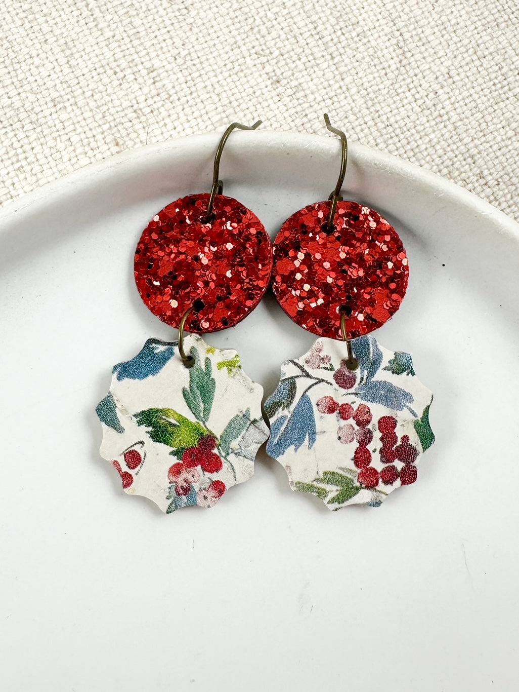 Winterberry Drop Earrings with red glitter circles and winter berry cork charms displayed on a white dish.